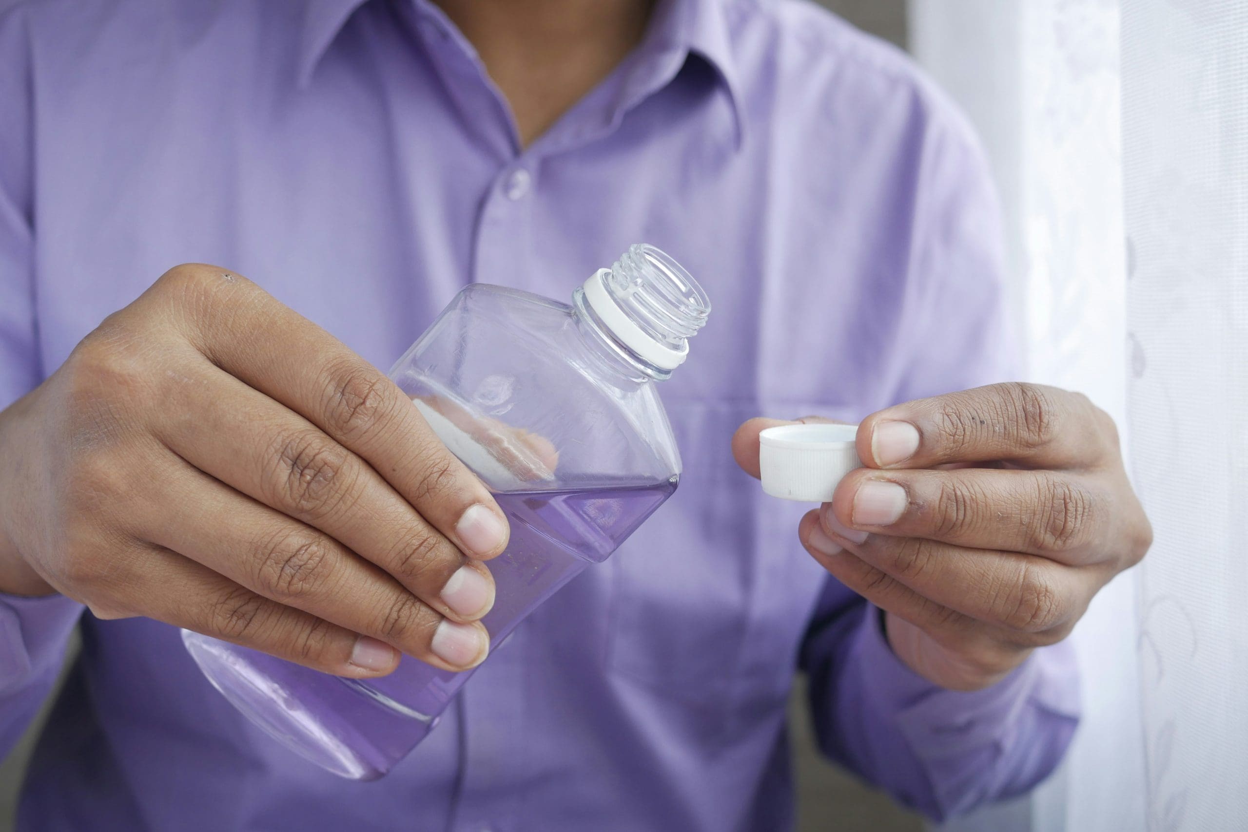 a person holding a bottle of mouthwash